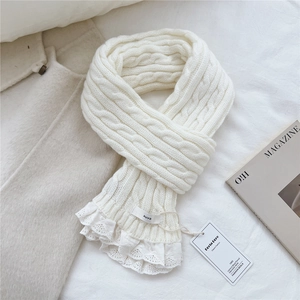 Detail view of cream knit scarf featuring cable stitch pattern and delicate white lace trim