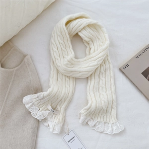 Close-up of cream knit scarf featuring chunky cable texture and delicate lace trim edges