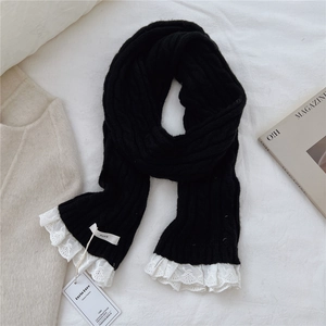 Close-up of black knit scarf featuring delicate white lace trim and brand woven label