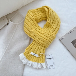Detail of yellow knit scarf with classic cable texture and delicate white lace trim