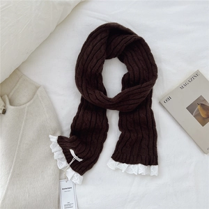 Close-up of brown cable knit scarf featuring white lace edges and a vintage texture