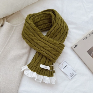 Detail of grass green chunky knit scarf with white lace trim and classic brand label