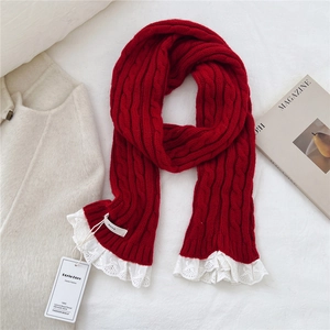Close-up of red cable-knit scarf with white lace trim and vintage style detail