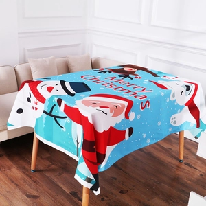 Detail of light blue Christmas tablecloth with Santa, snowman and elk prints on wood table
