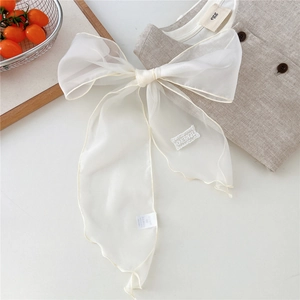 Detail of white sheer organza bow with embroidery label on a minimalist background