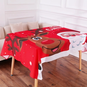 Detail of red Christmas tablecloth with cartoon Santa and reindeer on wooden table