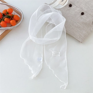 Close-up of lightweight white sheer scarf with embroidered label on a minimalist surface