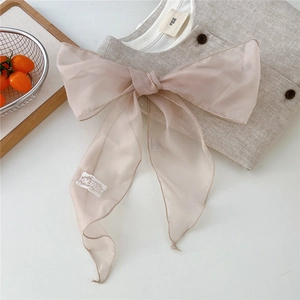 Detail of light pink organza bow scarf with white woven label on linen background