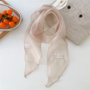 Detail of light beige chiffon scarf featuring a Onebagel embroidered patch and fine edging