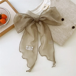 Detailed embroidery patch on a brown organza ribbon scarf with elegant wavy edges