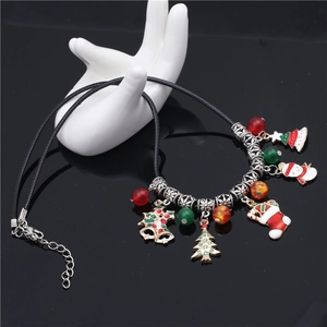 Christmas tree beaded necklace with snowman and bell charms on a white ceramic hand display