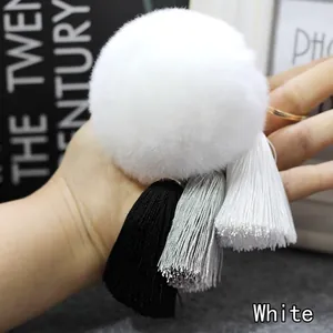 Detailoverzicht van witte faux fur pom-pom sleutelhanger met kwastjes