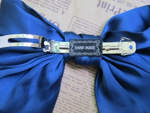 Nahaufnahme der dunkelblauen Satin-Schleife mit Hand-Made-Etikett und Metallspange