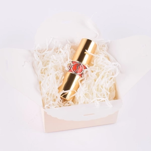 Golden lipstick with YSL logo in a gift box filled with white shredded raffia paper