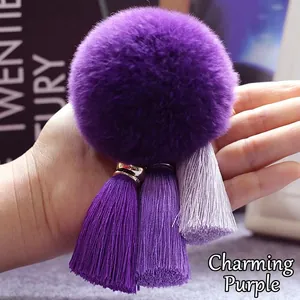 Dettaglio di un portachiavi a pompon in pelliccia viola con tre nappe sfumate per borse
