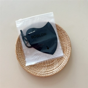 Detail of black breathable sun protection mask with adjustable ear loops in frosted bag