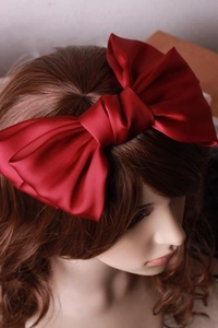 Detail einer großen weinroten Satin-Schleifen-Haarspange mit edlem Glanz auf dem Haar