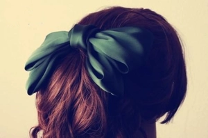 Detailansicht einer dunkelgrünen Satin-Schleife-Haarspange an langen Haaren
