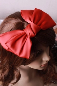 Makro-Detail einer großen roten Satin-Haarschleife zeigt Stofftextur und Volumen der Klammer