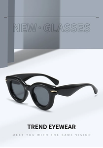 Detailed close-up of retro black bold frame sunglasses with golden metal hinge accents