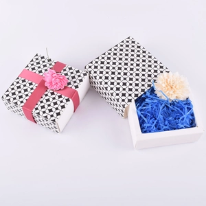 Close-up of geometric gift boxes with blue shredded paper filler and pink ribbon knot