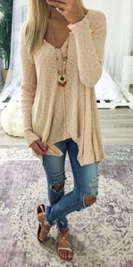 Detail of light apricot V-neck knit sweater with vertical ribbing and oversized hem