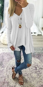 Detail of white waffle knit V-neck sweater showing its loose draped silhouette and textured fabric