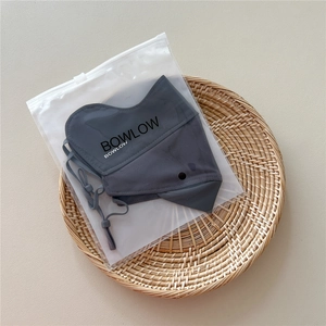Detail of grey sun protection mask with adjustable ear straps and branded storage bag