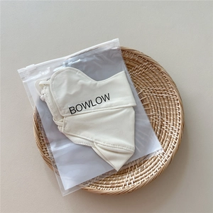 Detail of breathable cream sun mask with ear loops and branded packaging on a tray