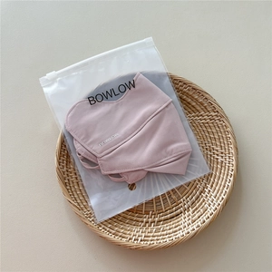 Close-up of pink breathable sun protection mask in branded zipper packaging on woven tray
