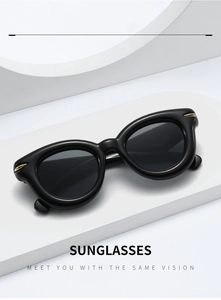 Detail view of black chunky frame sunglasses with gold metal accents on white geometric stand