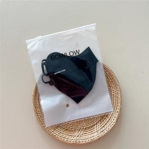 Detail view of black breathable sun protection face mask in a frosted zipper packaging bag
