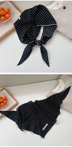 Detailed view of black polka dot neck scarf with delicate white lace trim and brand label
