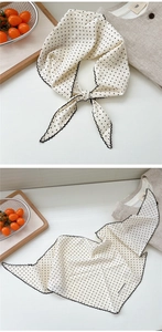 Close-up of white silk scarf with black polka dots and decorative wavy stitched edges