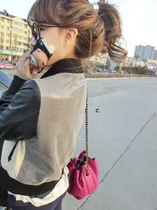 Detailed view of pink lychee textured bucket bag with gold chain strap on shoulder
