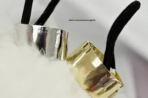 Macro view of gold and silver metal sleeves on minimalist elastic hair ties over faux fur