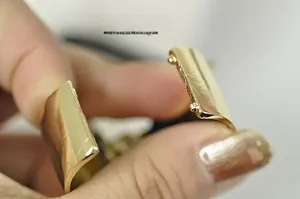 Macro detail of golden metal hair tie buckle featuring a brushed texture finish