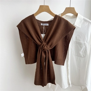 Detail of dark brown knitted shawl with cross-tie design layered over white shirt