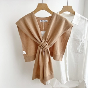 Detail of camel knitted shawl with cross-knot design over a white shirt for layering