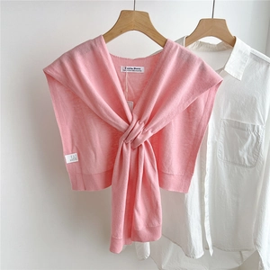 Detail of soft pink 100% wool knitted shawl with crossed knot design on white shirt