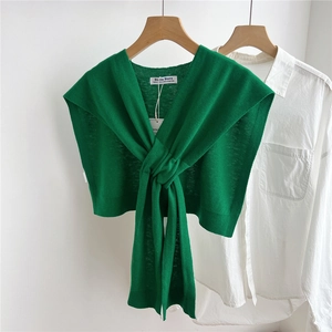 Close-up of emerald green knitted shoulder wrap with elegant front knot detail