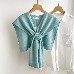 Close-up of mint green knitted wool shawl with knot design on white shirt
