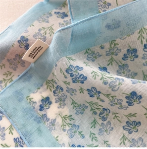 Macro detail of floral cotton linen blend scarf showing mesh texture and stitched edge