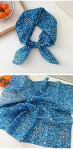 Detail of blue floral cotton linen scarf showing delicate print and knotted styling