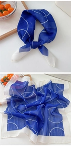 Close-up of royal blue square scarf with white geometric circles in a soft silk texture