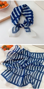 Detailed close-up showing light blue-white striped cotton linen scarf texture and material