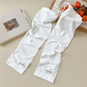 Detail of white knitted sun protection arm sleeves with textured ribbing and woven logo