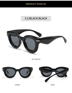 Detail view of oversized black bubble sunglasses with gold hinges and dark lenses