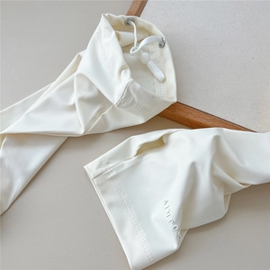 Detail of cream sun protection arm sleeve with drawstring closure and thumb hole design