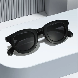 Classic black thick frame oval sunglasses with dark gradient lenses on a white pedestal